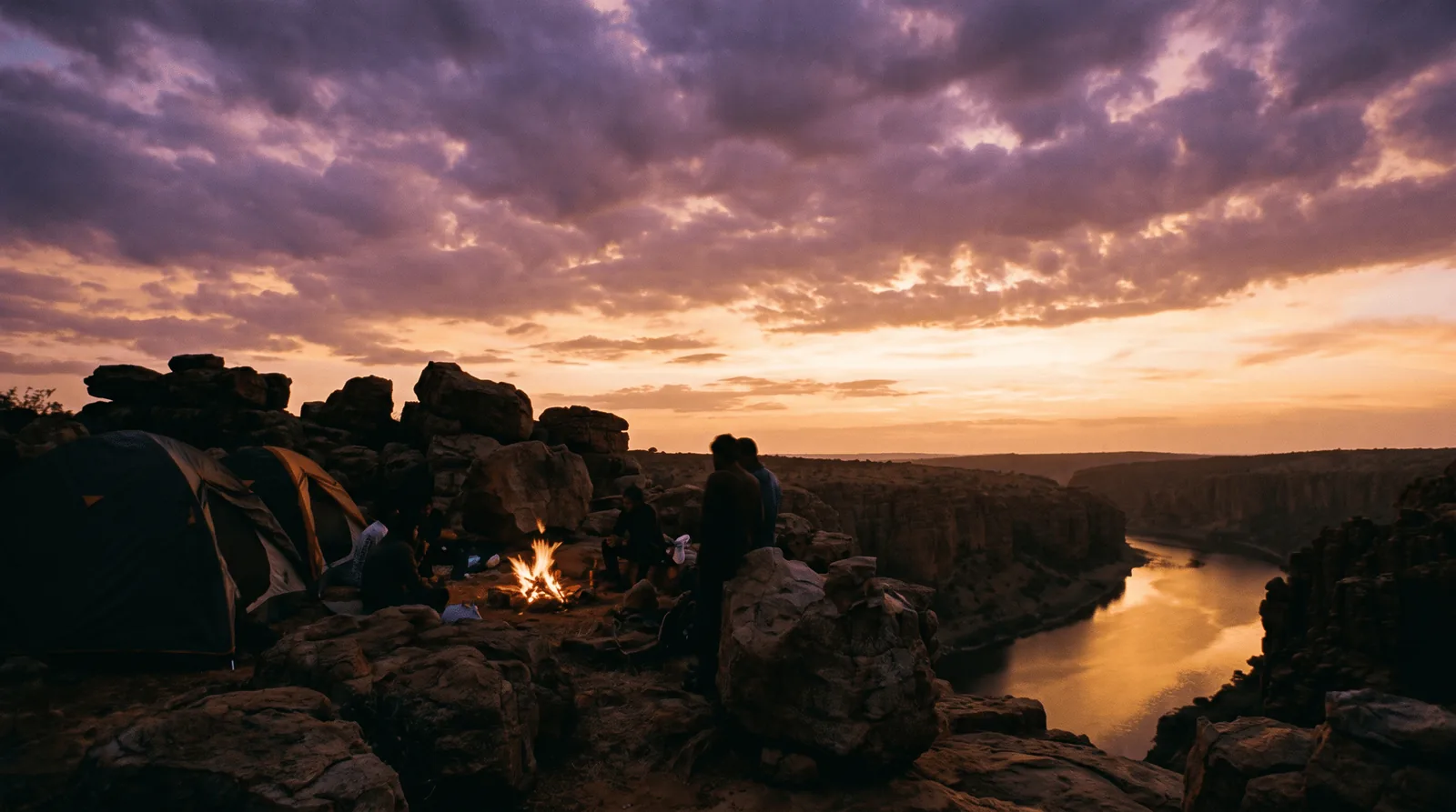 Tents and a campfire on the rim of the Gandikota canyon at sunset